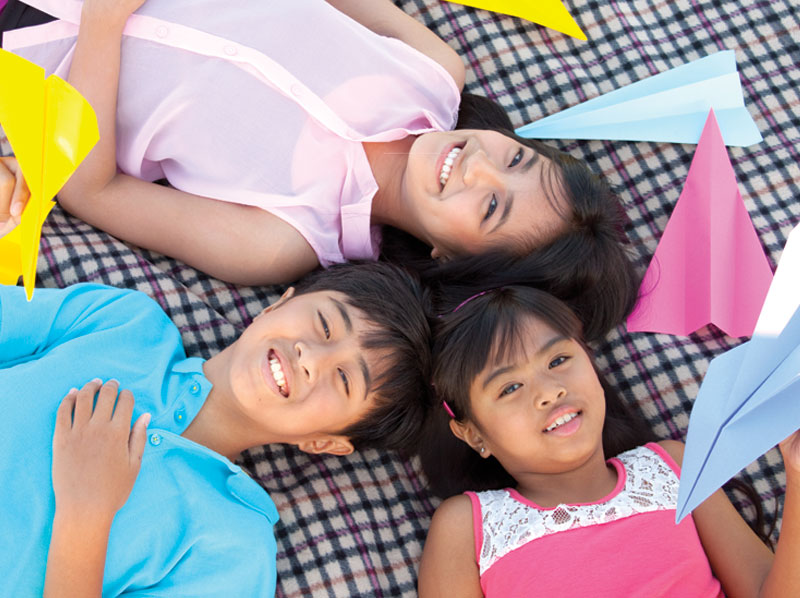 a boy and two girls with paper planes